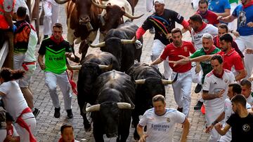El séptimo encierro de las fiestas de San Fermín discurrió sin incidentes reseñables. En la imagen se ve a algunos aficionados al fútbol, con camisetas del Real Madrid y de Osasuna, corriendo delante de los toros. A buen seguro que en su carrera añoraban la tranquilidad de ver el fútbol desde la grada, sin riesgos.