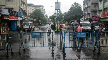 A police personnel in plain clothes (C) stands behind barricades set up on a street after a recent lockdown was reimposed in nine areas as a preventive measure against the COVID-19 coronavirus in Siliguri on July 9, 2020. (Photo by Diptendu DUTTA / AFP)