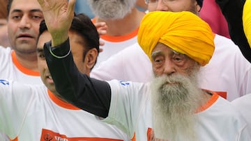 (FILES) Indian-born British national Fauja Singh (R) waves to the media after crossing the finish line in the 10-km event as part of the Hong Kong Marathon on February 24, 2013. India's Fauja Singh, believed to be the world's oldest distance runner, has died in a road accident aged 114, his biographer said on July 15, 2025. (Photo by Dale DE LA REY / AFP)