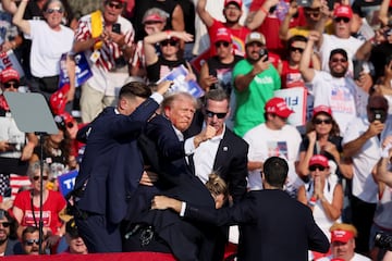 Former President Donald Trump is assisted by U.S. Secret Service personnel after gunfire rang out during a campaign rally at the Butler Farm Show in Butler, Pennsylvania.