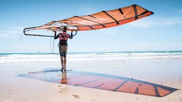 Participante en la Copa España Funboard aguantando su tabla y su vela en la playa de la Barrosa, Chiclana de la Frontera (Cádiz, España).