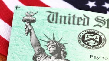 Cheque de est&iacute;mulo sobre la bandera de USA, v&iacute;a Getty Images.