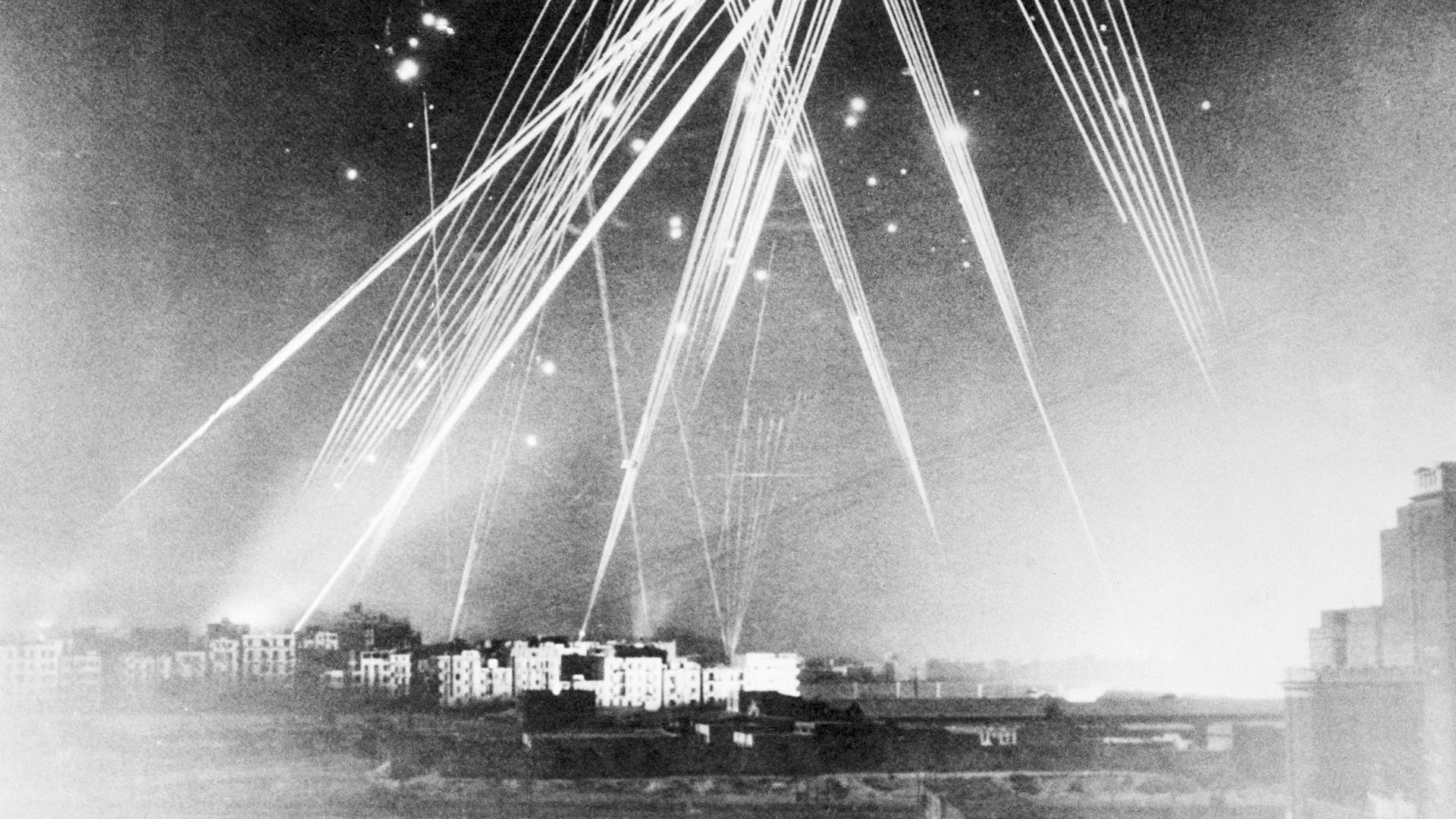 Mientras Jasper Maskelyne decía tener la solución para evitar los ataques, las fuerzas del Eje bombardeaban El Cairo. En la imagen, baterías antiaéreas en plena acción durante un ataque aéreo sobre Alejandría. En el fondo pueden verse explosiones de bombas.