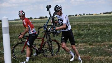 Great Britain's Christopher Froome (R) carries his bicycle next to Belgium's Jasper De Buyst after falling into a ditch in the last kilometers of the first stage of the 105th edition of the Tour de France cycling race between Noirmoutier-en-l�