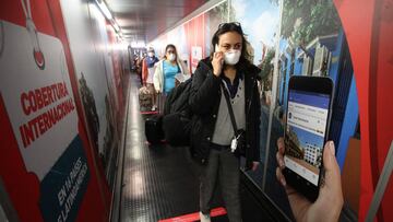 LIMA, PERU - JULY 15: A passenger wearing a face mask speaks on her cell phone before boarding a flight on July 15, 2020 in Lima, Peru. After four months, commercial domestic flights and long distance buses in Peru are allowed to operate again, following protocols against spread of COVID-19. Airports and bus stations will work on limited capacity. (Photo by Raul Sifuentes/Getty Images)