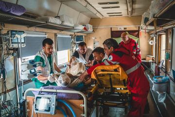 Un paciente gravemente herido de guerra es trasladado de una camilla de ambulancia a una cama dentro de la unidad de cuidados intensivos (UCI) del tren médico de MSF, que transporta heridos de guerra y personas gravemente enfermas desde el este de Ucrania hasta Lviv, en el oeste de Ucrania, donde pueden recibir la atención especializada que necesitan.