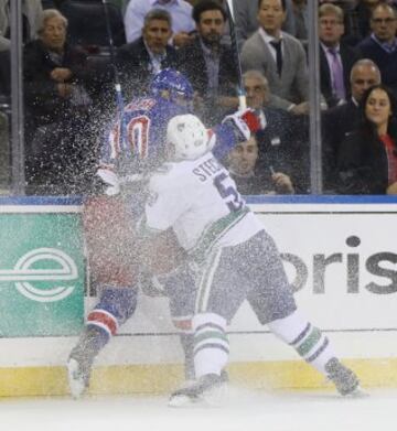 J.T. Miller de los New York Rangers es golpeado contra la valla por Troy Stecher de los Vancouver Canucks.