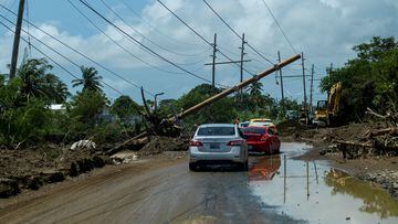 Cars drive under a downed power pole in the aftermath of Hurricane Fiona in Santa Isabel, Puerto Rico.