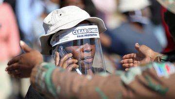 FILE PHOTO: A woman wears a protective face shield during food distribution, as South Africa starts to relax some aspects of a stringent nationwide coronavirus disease (COVID-19) lockdown, in Diepsloot near Johannesburg, South Africa, May 8, 2020. REUTERS