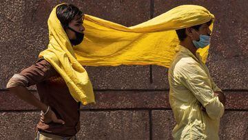 Migrant workers cover themselves with a scarf, to protect from heat as they wait to get registered before boarding a train to their home state of eastern Bihar, during an extended lockdown to slow the spreading of the coronavirus disease (COVID-19), in Ne