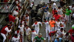 Participants run ahead of bulls during the "encierro" (bull-run) of the San Fermin festival in Pamplona, northern Spain on July 9, 2022. - On each day of the festival six bulls are released at 8:00 a.m. (0600 GMT) to run from their corral through the narrow, cobbled streets of the old town over an 850-meter (yard) course. Ahead of them are the runners, who try to stay close to the bulls without falling over or being gored. (Photo by MIGUEL RIOPA / AFP)