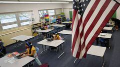 ARCHIVO - En esta fotograf&iacute;a de archivo del martes 25 de agosto de 2020, una bandera estadounidense cuelga en un sal&oacute;n de clases mientras los estudiantes trabajan en computadoras port&aacute;tiles en la escuela primaria Newlon.