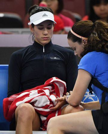 Garbine Muguruza is attended to by a trainer before retiring from her women's singles match.
