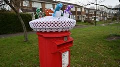 A Christmas-themed decoration, featuring knitted snowmen, is pictured on the top of a traditional red Royal Mail post box in Shoreham, southern England on December 22, 2021.