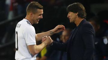 Lukas Podolski shakes hands with coach Joachim Low as he walks off to be substituted