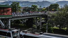 People wait in line on a bridge as they commute near a metro station on their way home before a curfew, amid the COVID 19 pandemic in Medellin, Colombia on March 31, 2021. - Authorities placed several regions including Antioquia department and its capital Medellin under a new lockdown after an increase in coronavirus cases. (Photo by JOAQUIN SARMIENTO / AFP)
