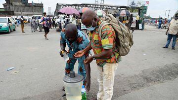 A traveller (R) sanitises his hands in compliance with measures at the bus terminal to curtail the spreads of COVID-19 coronavirus following the ease of interstate travels at the Ojota bus terminal in Lagos, on July 1, 2020. - Bus terminals across the cou