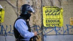 PHILADELPHIA, PA - OCTOBER 28: A police officer walks past a sign that reads &quot;ENOUGH GO VOTE&quot; sign and graffiti that reads &quot;WALTER WALLACE RIP&quot; an hour before a citywide curfew, on October 28, 2020 in Philadelphia, Pennsylvania. Mayor 