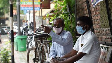 Men wearing protective facemasks as a preventive measure against the spread of the COVID-19 coronavirus, sit on a public bench in Ahmedabad on August 17, 2020. - India&#039;s official coronavirus death toll soared past 50,000 on August 17 as the pandemic 