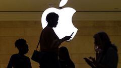 FILE PHOTO: A women uses an iPhone mobile device as she passes a lighted Apple logo at the Apple store at Grand Central Terminal in New York City, U.S., April 14, 2023. REUTERS/Mike Segar/File Photo