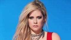 Avril Lavigne, con el pelo rubio, un vestido rojo, collares y el fondo azul, mirando a c&aacute;mara. 
