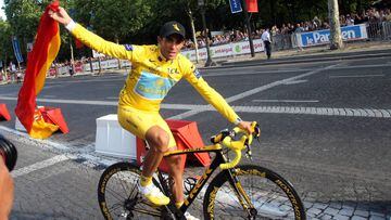 Alberto Contador rueda por las calles de Par&iacute;s con el maillot amarillo y la bandera de Espa&ntilde;a tras ganar el Tour de Francia 2009.