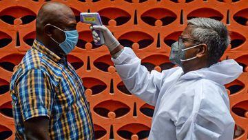 A doctor (R) checks the body temperature of a man at a containment zone implemented as a preventive measure against the COVID-19 coronavirus in Chennai on July 30, 2020. (Photo by Arun SANKAR / AFP)