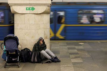 A young man with a stroller rests on the floor of a Kyiv underground station as he takes refuge from possible Russian air attacks.