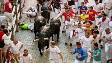 Participants run ahead of bulls during the "encierro" (bull-run) of the San Fermin festival in Pamplona, northern Spain on July 13, 2022. - On each day of the festival six bulls are released at 8:00 a.m. (0600 GMT) to run from their corral through the narrow, cobbled streets of the old town over an 850-meter (yard) course. Ahead of them are the runners, who try to stay close to the bulls without falling over or being gored. (Photo by MIGUEL RIOPA / AFP) (Photo by MIGUEL RIOPA/AFP via Getty Images)